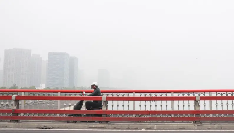 cyclist on a bridge against a foggy city backdrop